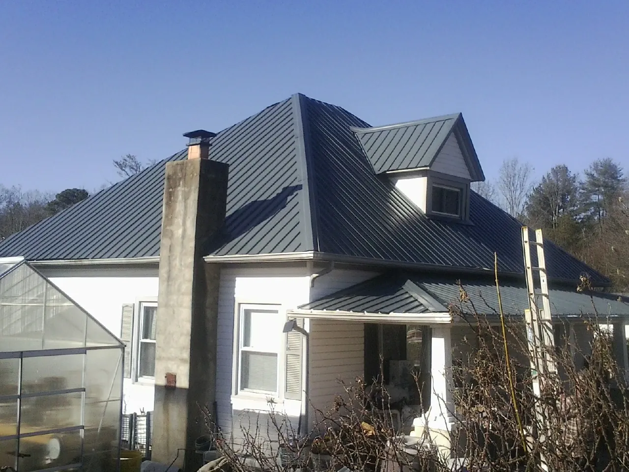 Dark blue standing seam metal roof on a white farmhouse with dormer — Slate & Tile Roof Repair by Roofing Brothers in Temple City