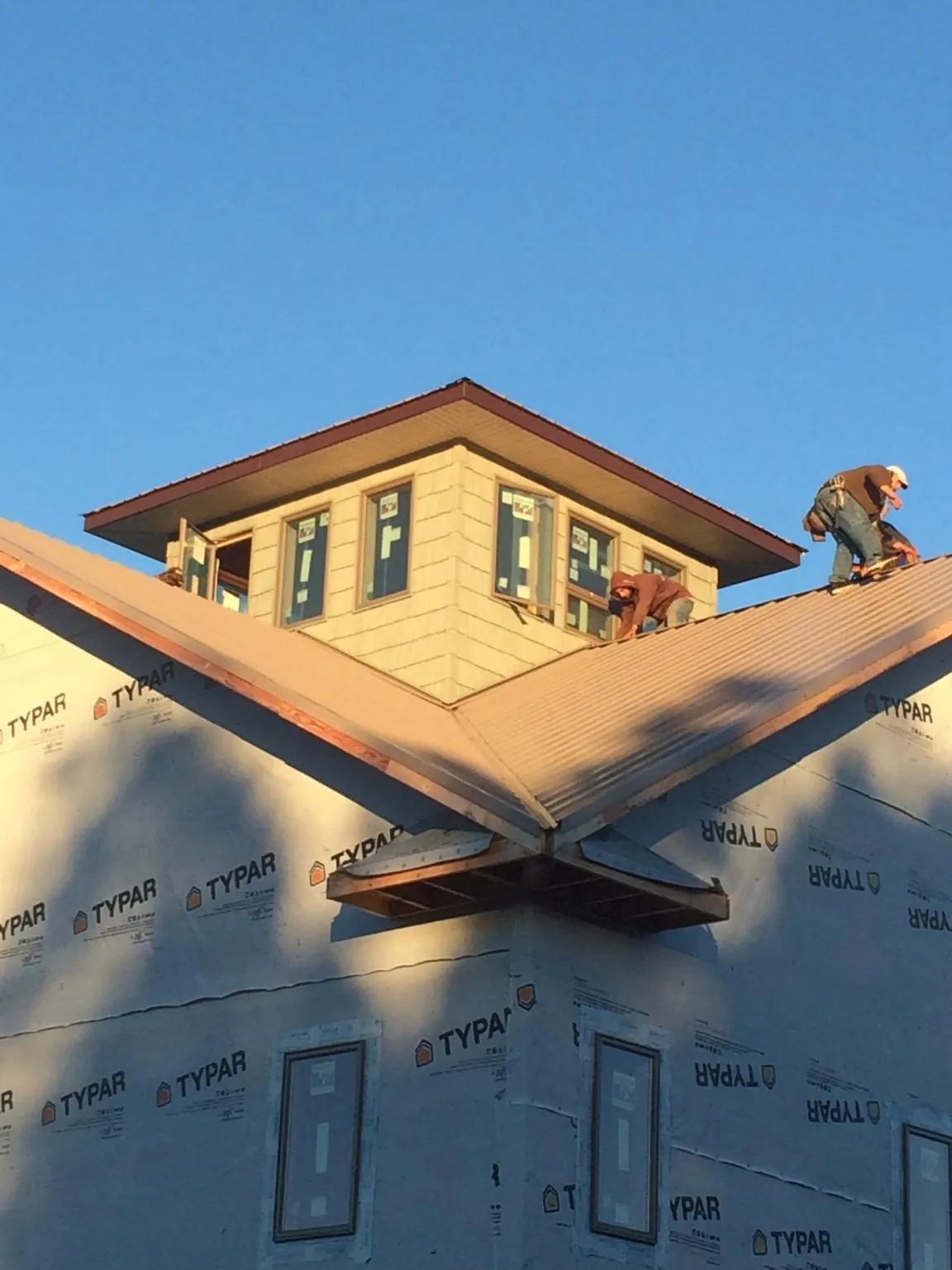 Roofers working around a rooftop cupola on a new metal roof at sunset — Roof Waterproofing in Temple City by Roofing Brothers
